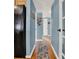 A long hallway with wood floors and light blue walls, featuring a view to an adjacent kitchen at 4015 Ibis Dr, Orlando, FL 32803