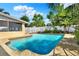 Backyard pool surrounded by a concrete patio, white fence, and tropical landscaping on a sunny day at 4015 Ibis Dr, Orlando, FL 32803