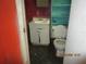 Small bathroom in disrepair features a toilet, sink and teal shelving at 4231 Raleigh St, Orlando, FL 32811