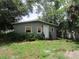 Exterior of a single-story home with boarded windows and overgrown lawn at 4231 Raleigh St, Orlando, FL 32811