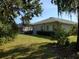 Spacious backyard with lush green grass, mature trees, and partial view of a screened lanai at 4351 Winding Oaks Cir, Mulberry, FL 33860