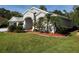 Beautiful home showcasing lush green lawn, manicured garden beds, and stately architectural features at 4351 Winding Oaks Cir, Mulberry, FL 33860