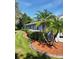 Side yard featuring palm trees, manicured shrubs, and well-maintained lawn with concrete curbing at 4351 Winding Oaks Cir, Mulberry, FL 33860