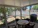 Enclosed patio features a round table and chairs, offering a cozy outdoor space with backyard views and a white fence at 436 Hammerstone Ave, Haines City, FL 33844