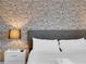 Close-up of the bed with unique newspaper accent wall and modern lamp at 4530 Narrative Ln, Kissimmee, FL 34746