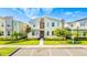 Modern townhouse with a red door, stone accents, a well-manicured lawn, and dedicated parking spaces at 4530 Narrative Ln, Kissimmee, FL 34746