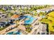 Aerial view of a community pool with seating, palm trees, and sunshades, surrounded by numerous homes at 4530 Narrative Ln, Kissimmee, FL 34746