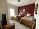 Bright second bedroom furnished with two twin beds and a decorative red accent wall at 5370 Diplomat Ct # 107, Kissimmee, FL 34746