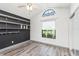 This bedroom features wood-look floors, built-in shelving, a modern ceiling fan, and a large window at 685 Middlebury Loop, New Smyrna Beach, FL 32168