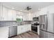 Stylish kitchen with white cabinets, granite countertops, stainless steel appliances and modern tile backsplash at 685 Middlebury Loop, New Smyrna Beach, FL 32168