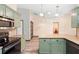 An updated kitchen with green cabinets, granite countertops, and stainless-steel appliances offering a blend of style and functionality at 6906 Sawmill Blvd, Ocoee, FL 34761