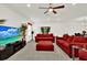 Bright living room featuring a large flat-screen TV, ceiling fan, and comfortable red sofas for a relaxing atmosphere at 804 Glen Creek Ct, Fruitland Park, FL 34731