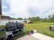 Spacious backyard featuring a large grassy area, white fence, and patio with grilling area, perfect for outdoor entertaining at 8710 Rindge Rd, Polk City, FL 33868