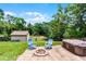 Serene backyard with a fire pit, hot tub, storage shed, and green lawn at 891 Licaria Dr, Ocoee, FL 34761