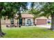 Inviting home exterior with a well-maintained lawn, trees, and quaint front porch furniture at 891 Licaria Dr, Ocoee, FL 34761