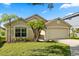 Inviting single-story home with a manicured lawn, palm trees, and a two-car garage on a sunny day at 8920 Palisades Beach Ave, Orlando, FL 32829