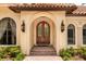Close-up of the arched wood double-door entrance with brick steps and lantern sconces at 9253 Tibet Pointe Cir, Windermere, FL 34786