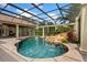 Beautiful swimming pool with rock waterfall, lush landscaping, screened enclosure, and outdoor kitchen at 9253 Tibet Pointe Cir, Windermere, FL 34786