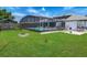 Manicured backyard with a screened-in pool, a fire pit, and green grass at 1129 Madura Dr, Deltona, FL 32725
