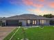 Charming home with manicured lawn, rock border, modern exterior lighting and walkway to front door at 1129 Madura Dr, Deltona, FL 32725