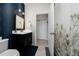 Bathroom with blue accent wall, black vanity, modern mirror and lighting fixtures at 15693 Kinnow Mandarin Ln, Winter Garden, FL 34787