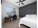Well-lit bedroom featuring a ceiling fan, dark accent wall, and a view of the front yard at 15693 Kinnow Mandarin Ln, Winter Garden, FL 34787