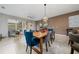 Open-concept dining area with a wooden table, plush chairs, and modern lighting fixture at 15693 Kinnow Mandarin Ln, Winter Garden, FL 34787