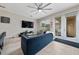 Stylish living room with a plush blue sofa, modern ceiling fan, and access to outdoor patio at 15693 Kinnow Mandarin Ln, Winter Garden, FL 34787