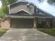 Charming two-story home featuring a brick and gray wood exterior with a two-car garage and a well-maintained front yard at 2181 Wekiwa Oaks Dr, Apopka, FL 32703