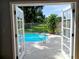 View of a sparkling blue pool from inside the home, framed by open French doors at 2181 Wekiwa Oaks Dr, Apopka, FL 32703