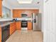 Well-lit kitchen featuring stainless steel appliances, wood cabinets, and neutral countertops and tile flooring at 2311 Chatham Place Dr, Orlando, FL 32824