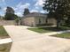 View of a tan single-story home featuring an attached garage, a long driveway, and manicured landscaping at 2555 Palmetto Ridge Cir, Apopka, FL 32712