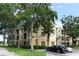 Beige three-story condo building with mature trees, manicured shrubs, and assigned parking at 2598 Robert Trent Jones Dr # 1030, Orlando, FL 32835