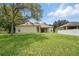 Lush backyard with a well-manicured lawn, mature trees, and a covered patio that provides a relaxing outdoor space at 2674 Spicebush Loop, Apopka, FL 32712