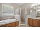 Bathroom features tile flooring, a glass-enclosed shower, a tub, and double sinks at 2674 Spicebush Loop, Apopka, FL 32712