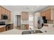Modern kitchen with stainless steel appliances, wooden cabinetry, and a view into the adjacent dining area at 2674 Spicebush Loop, Apopka, FL 32712