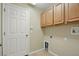 This laundry room features wood upper cabinets, utility hookups, tiled floors, and a white door at 2674 Spicebush Loop, Apopka, FL 32712