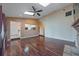 Open-concept living room with wood floors, skylights, and a view into the kitchen area at 2715 Wekiva Meadows Ct, Apopka, FL 32712