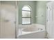 Well-lit bathroom with a glass-enclosed shower, soaking tub beneath an arched window, and white tile at 2933 Birmingham Blvd, Orlando, FL 32829