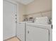Bright laundry room with a stacked washer and dryer, storage shelf and a door at 3018 Bransbury Ct, Kissimmee, FL 34747
