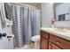 Neutral bathroom featuring a single sink vanity and a tub and shower combination with patterned shower curtain at 3822 Janie Ct, Orlando, FL 32822