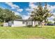 A view of the side of the home with a large yard and mature trees at 3822 Janie Ct, Orlando, FL 32822
