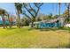 Charming exterior showcases a well-manicured lawn with mature trees and a quaint blue house at 400 Palm Ave, Ormond Beach, FL 32174