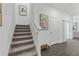 A carpeted staircase ascending past modern art, contrasting gray wood floors, and a bright, airy landing at 490 Belmond Dr, Debary, FL 32713