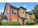Two-story townhome showing stucco exterior, black trim, well-maintained landscaping, and a blue sky background at 6001 Westgate Dr # 2124, Orlando, FL 32835