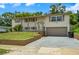 Split-level home with 1 car garage, light-colored paint, and neatly kept landscaping and lawn at 6416 Jackwood Ct, Orlando, FL 32818