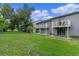 View of the building's backyard, featuring lush green grass, two balconies and sliding glass doors at 7449 Daniel Webster Dr # 3, Winter Park, FL 32792