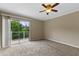 Carpeted bedroom with a ceiling fan and a sliding glass door that opens to a small balcony at 7449 Daniel Webster Dr # 3, Winter Park, FL 32792