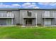 A view of the building with white balconies and glass doors overlooking the green lawn at 7449 Daniel Webster Dr # 3, Winter Park, FL 32792