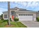 Inviting exterior view of home featuring a two-car garage, lush lawn and a bright red front door at 8113 Sun Palm Dr, Kissimmee, FL 34747